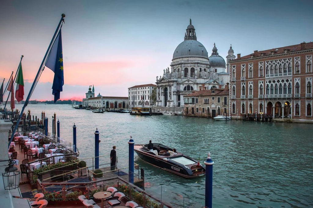 Historic Gritti Palace hotel in Venice with ornate Gothic architecture, marble columns, and waterfront terrace overlooking the Grand Canal