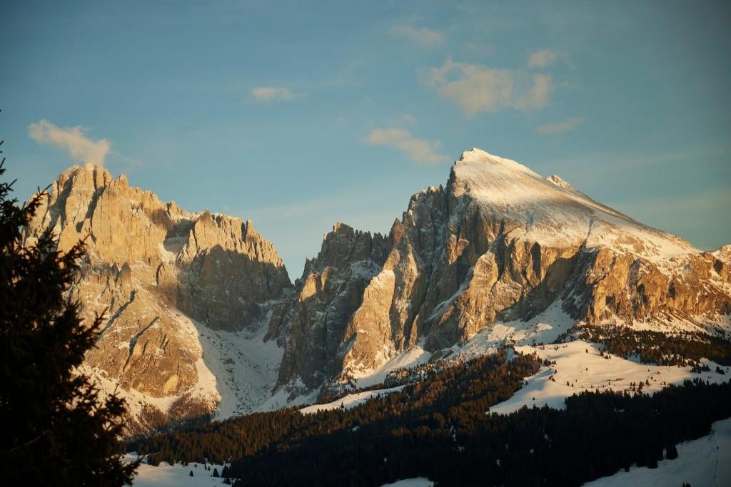 Luxurious mountain resort with glass facade nestled in snowy Dolomites, featuring modern architecture and panoramic Alpine views