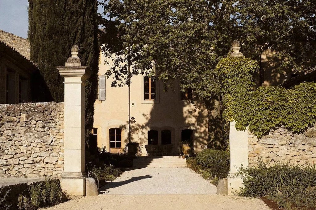 Luxurious stone-facade French boutique hotel with rustic Provençal charm, terracotta roof, and lush garden in picturesque southern France landscape