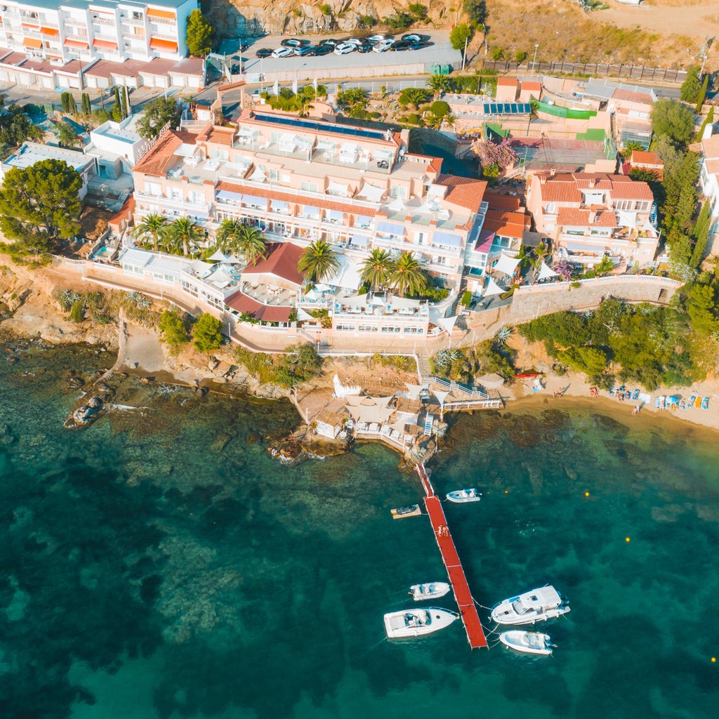 Five-star Hotel Vistabella's white Mediterranean facade with elegant balconies overlooks the Costa Brava coastline at sunset