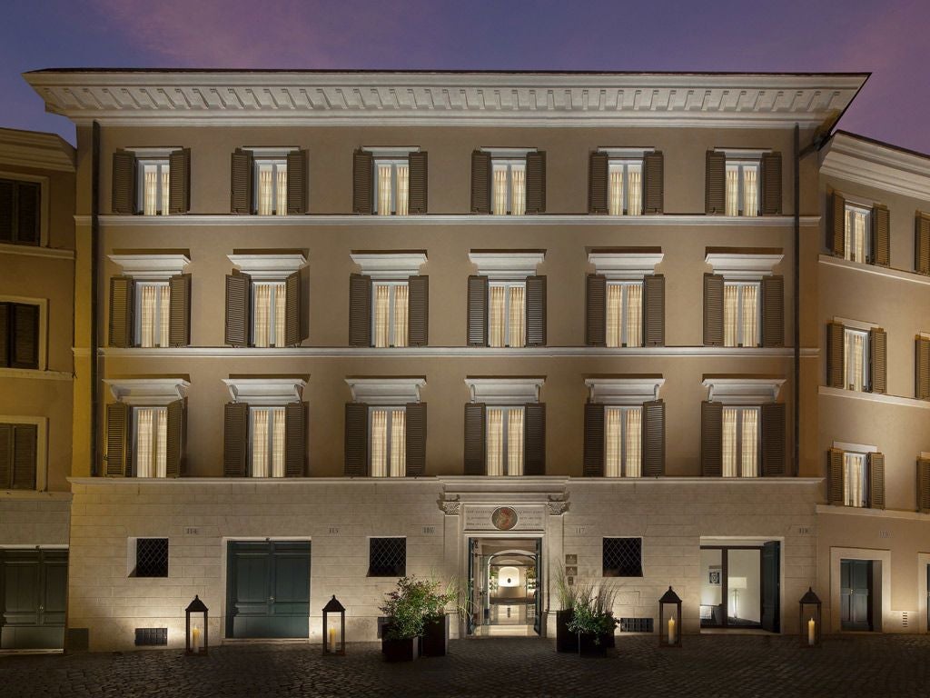 Elegant Renaissance-style palazzo in Rome with cream-colored facade, ornate balconies, and classic Italian architectural details against soft golden sunlight