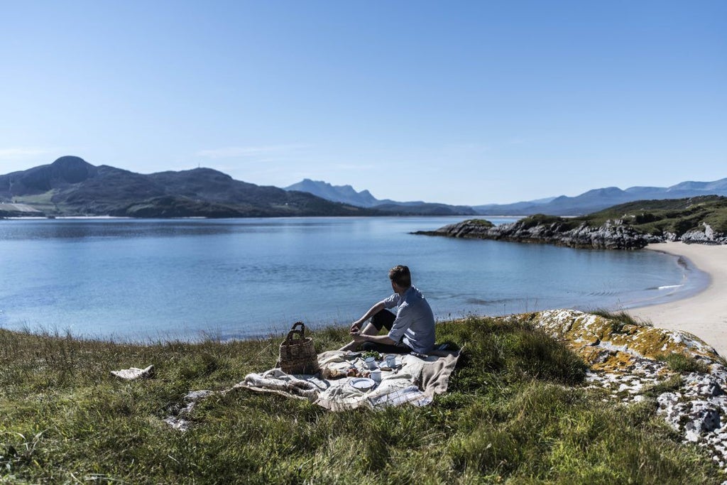 Historic stone Kinloch Lodge nestled in Scottish highlands, with manicured gardens, overlooking misty Loch na Dal at sunrise