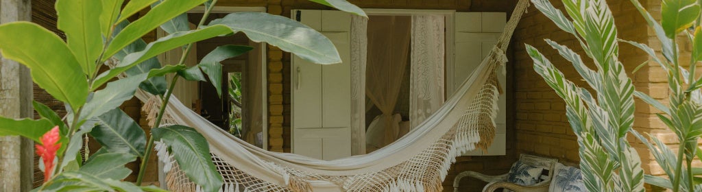 Spacious Brazilian hotel room with elegant wooden furniture, crisp white linens, and warm tropical decor overlooking lush green landscape at Pousada Capim Santo