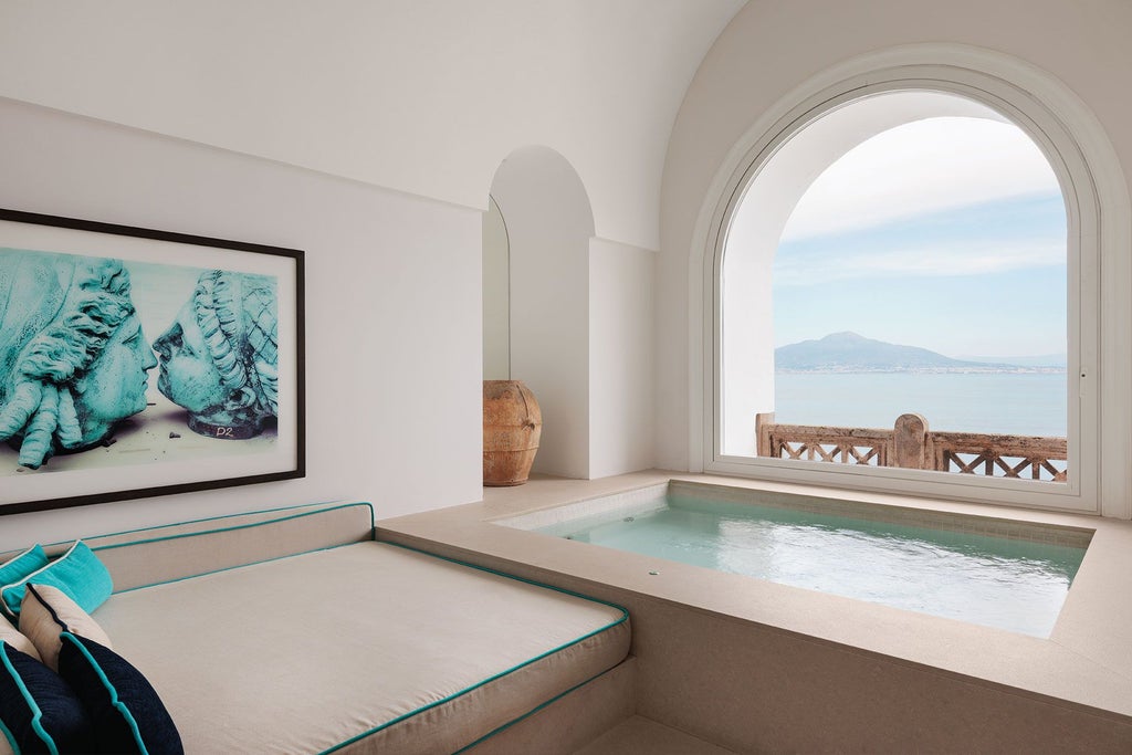 Opulent suite with panoramic Mediterranean coastline, elegant marble floors, plush white furnishings, and sweeping azure sea view from ornate balcony in Sorrento, Italy