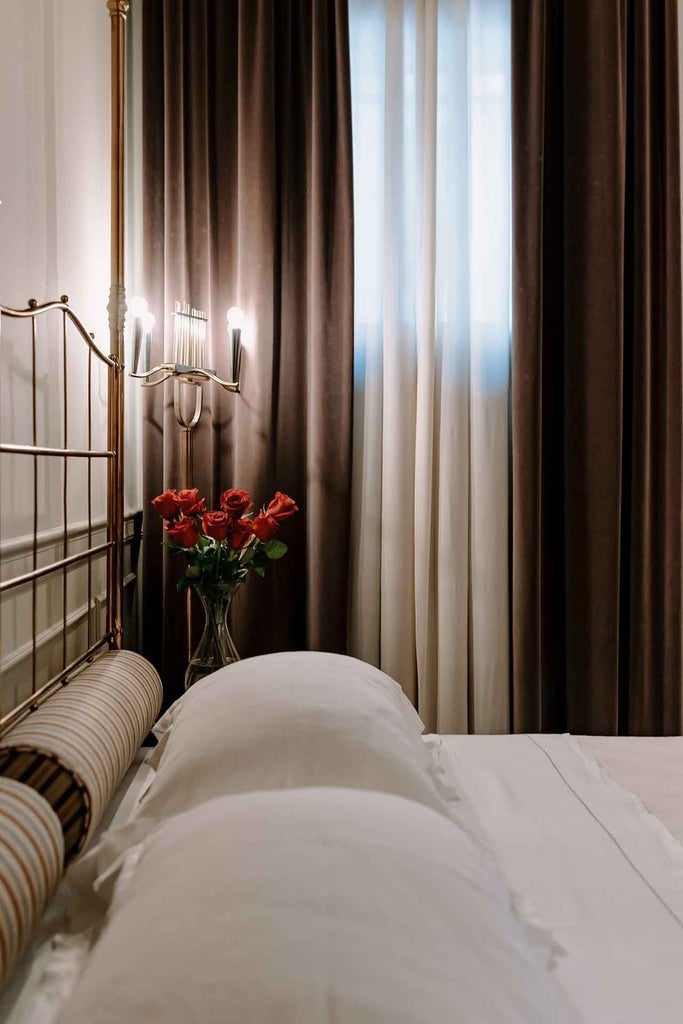 Elegant Italian suite with plush white bedding, soft neutral tones, minimal wooden furniture, and warm ambient lighting in a sophisticated boutique hotel room