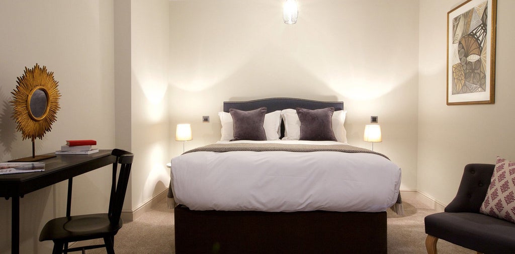 Spacious, elegantly furnished hotel room with modern amenities, plush king-sized bed, and contemporary decor at Kings Head Hotel Apartments in the United Kingdom.