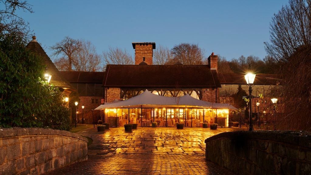 Elegant stable-converted luxury hotel room at Coworth Park, featuring rustic wood accents, plush bedding, and sophisticated equestrian-inspired design elements