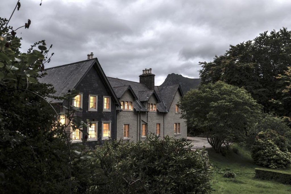 Historic stone manor Kinloch Lodge nestled in Scottish Highlands, surrounded by mountains and water, with manicured gardens at dusk