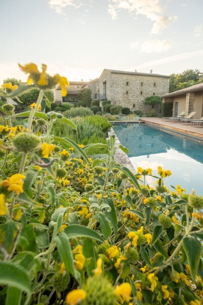 Rustic stone facade of luxurious French boutique hotel nestled in Provence, with lavender fields and terracotta roof against soft golden sunlight