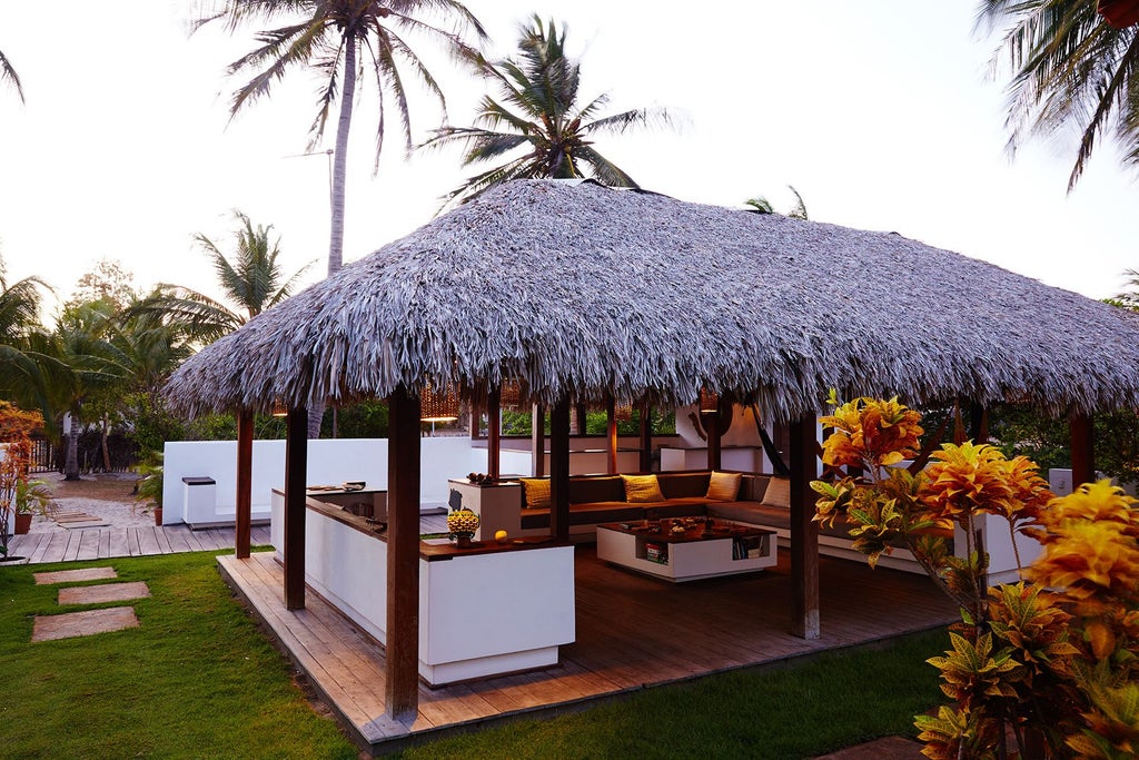 Luxurious rustic Brazilian hotel with white-washed stone walls, wooden balconies, and lush tropical landscaping nestled in verdant countryside