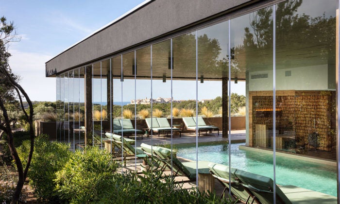 Elegant clifftop hotel overlooking the Mediterranean Sea, featuring stone walls, infinity pool and panoramic terraces in Corsica, France