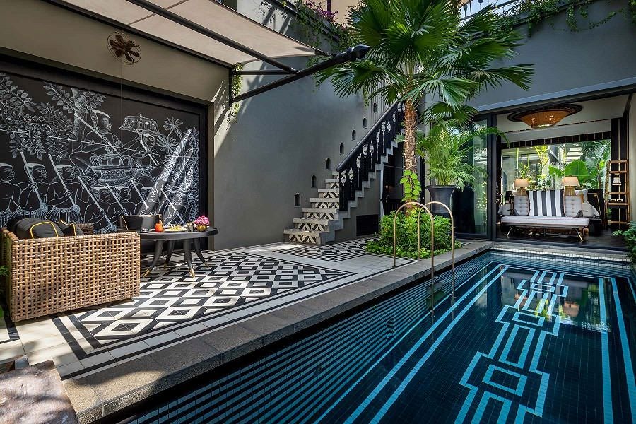 Luxurious Cambodian villa bedroom with floor-to-ceiling windows, modern canopy bed, geometric patterns and private pool glimpse