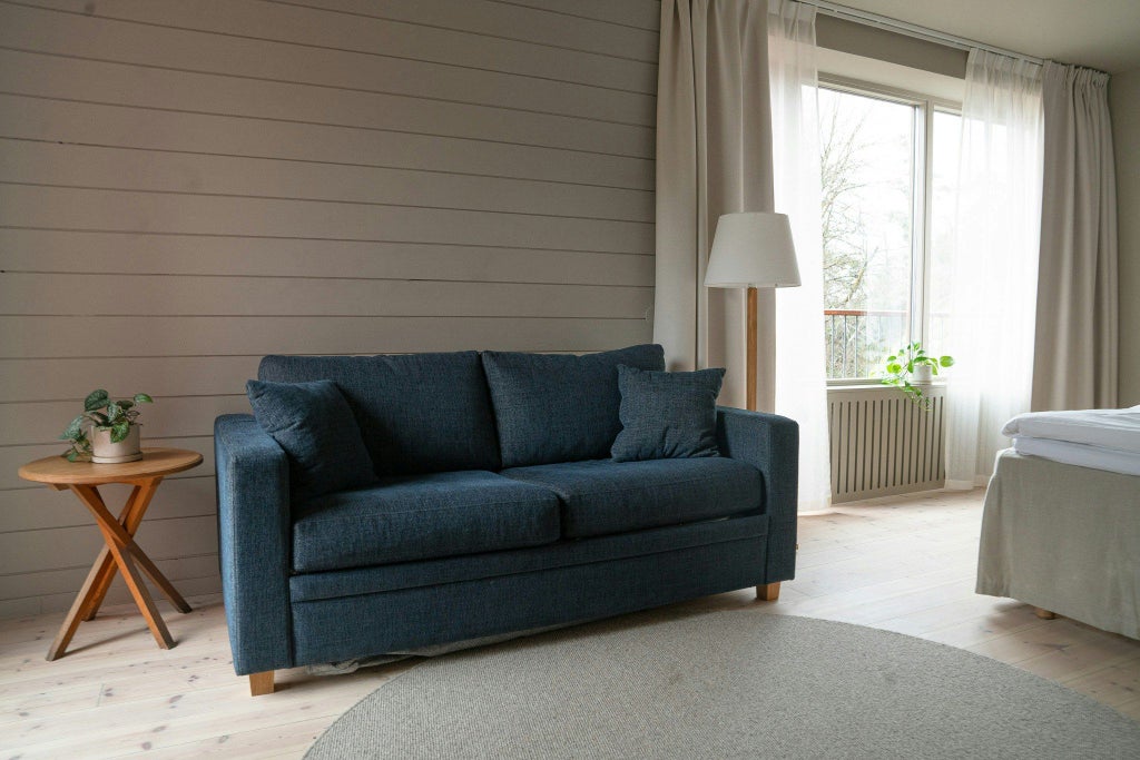 Spacious deluxe family room with modern Scandinavian design, featuring plush beds, warm wood tones, large windows, and elegant minimalist decor in a Swedish hotel setting