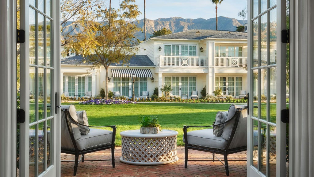 Elegant garden bungalow suite at luxurious Scenset Miramar Beach resort, featuring plush white bedding, coastal-inspired decor, and private outdoor seating area