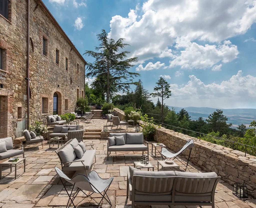 Sunlit stone villa in Tuscany with rustic wooden shutters, terracotta roof tiles, and climbing vines, set against rolling hills at golden hour