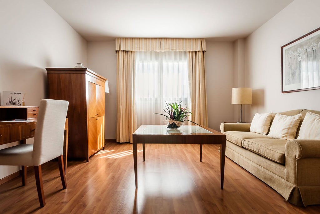 Spacious modern junior suite with elegant neutral decor, large windows, plush king bed, and sleek contemporary furnishings in boutique Spanish hotel room