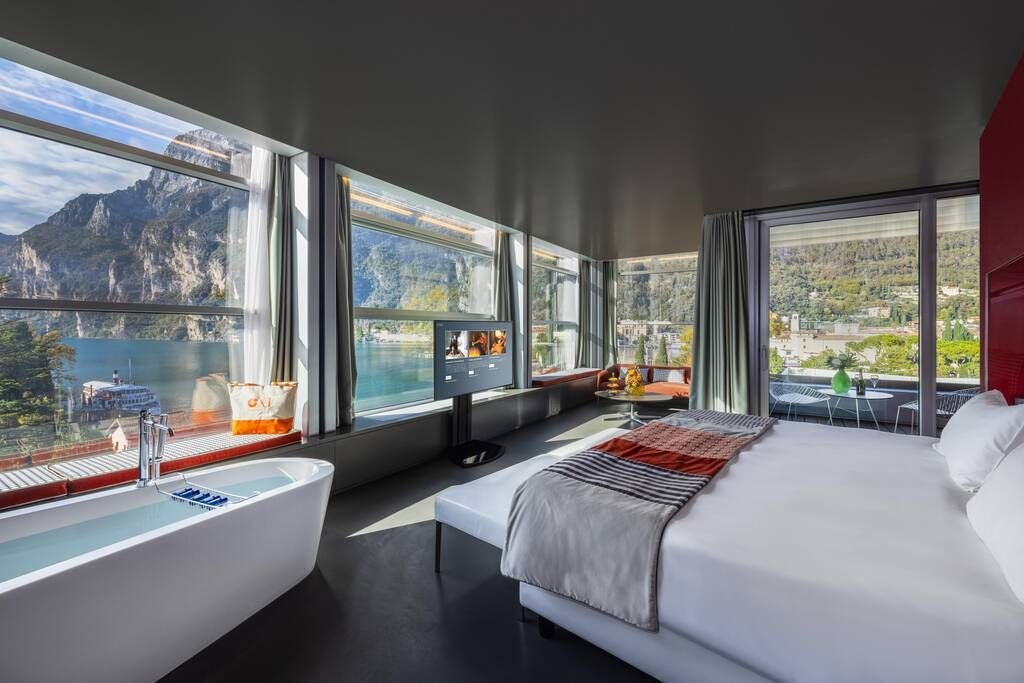 Elegant Sky Signature Suite at Lido Palace, featuring panoramic windows, contemporary Italian design, and plush king bed with sweeping alpine mountain landscape views