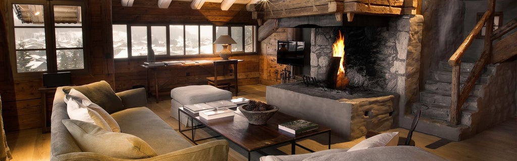 Luxurious Alpine chalet bedroom with elegant wooden furnishings, warm neutral tones, and stunning mountain view through large panoramic window at scenic mountain resort