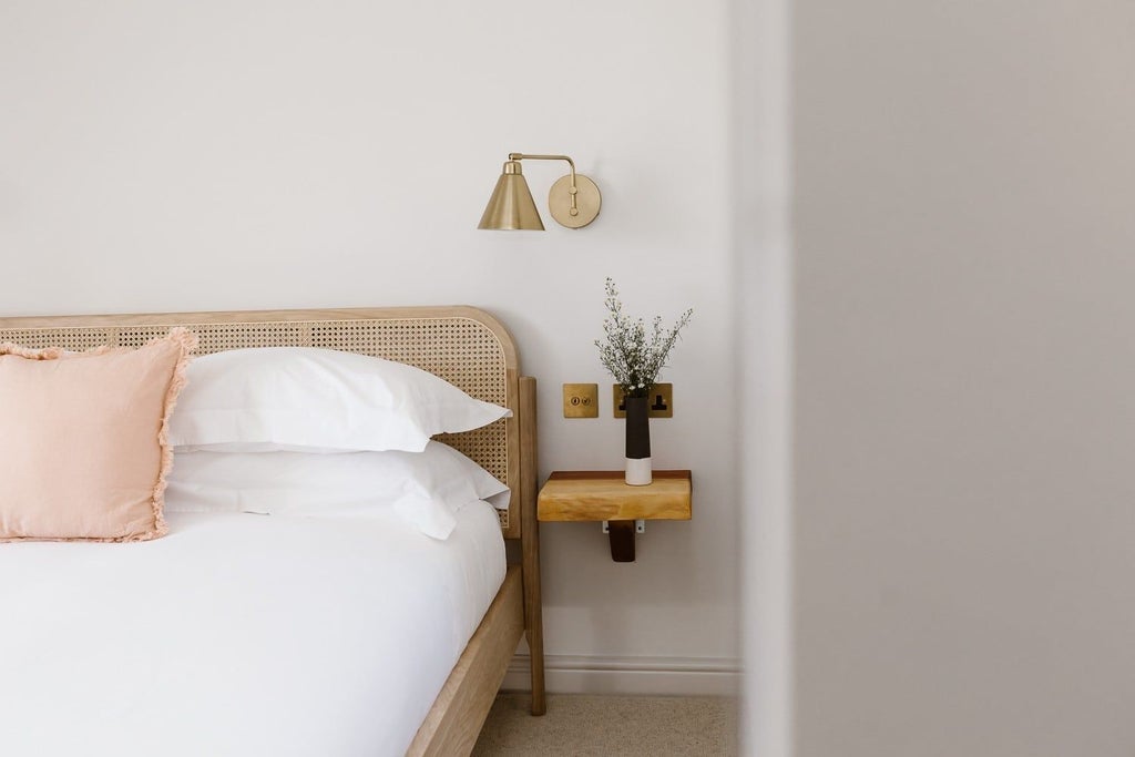 Elegant coastal-inspired hotel bedroom with plush white bedding, soft neutral tones, and serene seaside view at The Sandy Duck accommodation in United Kingdom