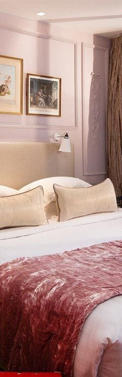 Elegant Parisian hotel room with soft blush and cream tones, luxurious king bed, ornate chandeliers, and sophisticated French romantic design aesthetic