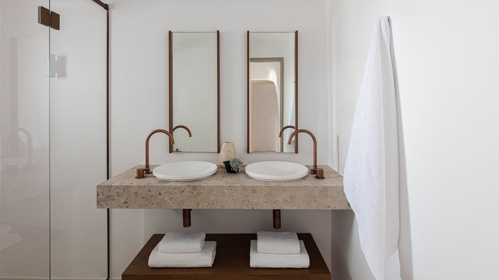 Spacious luxurious two-bedroom suite in Santorini with white minimalist design, panoramic sea view, private pool, and elegant contemporary Greek island styling