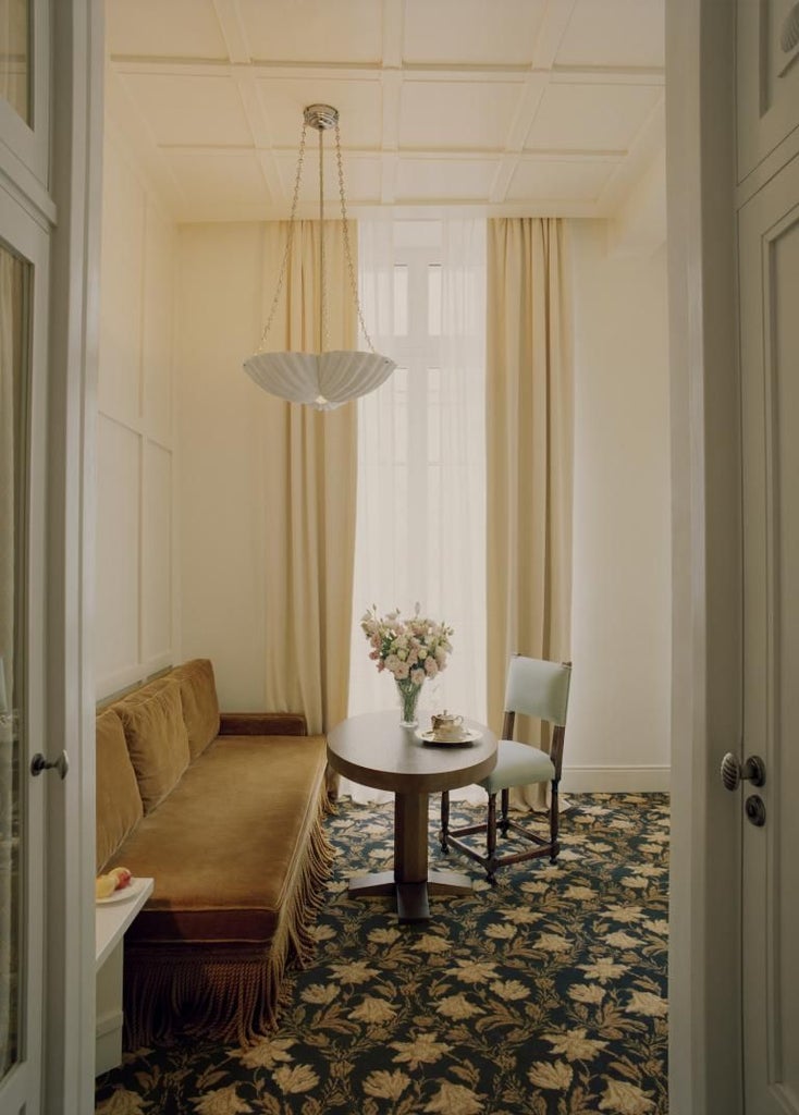 Elegant French boutique hotel exterior with cream-colored facade, arched windows, and wrought-iron balconies in historic Parisian architectural style