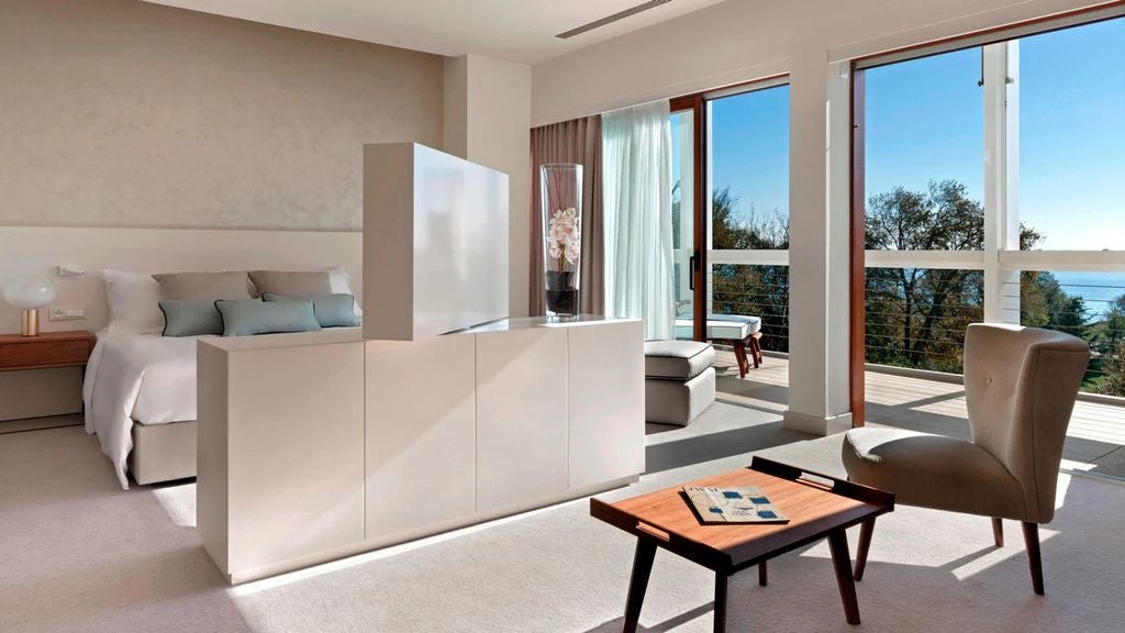 Elegant Junior Suite with private terrace in Venice, featuring modern decor, king bed, lounge area and panoramic lagoon views.