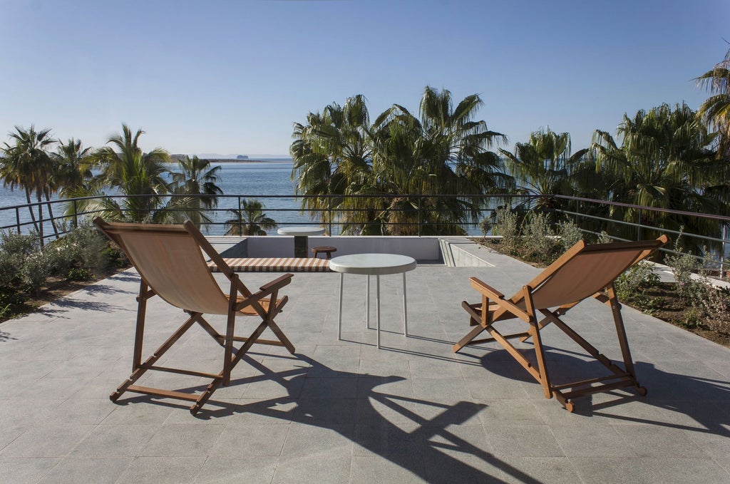 Luxurious beachfront hotel with white stucco architecture, blue pool overlooking azure waters, and palm trees at scenset in coastal Mexico.