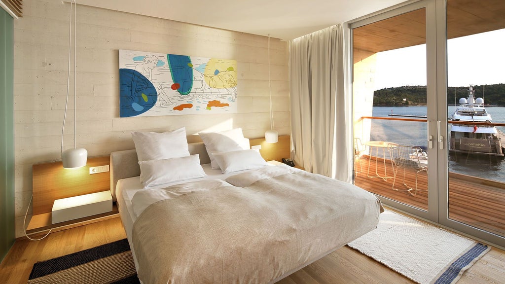 Spacious deluxe hotel room with modern minimalist design, featuring elegant wooden furnishings, pristine white bedding, and panoramic sea view in Šibenik, Croatia