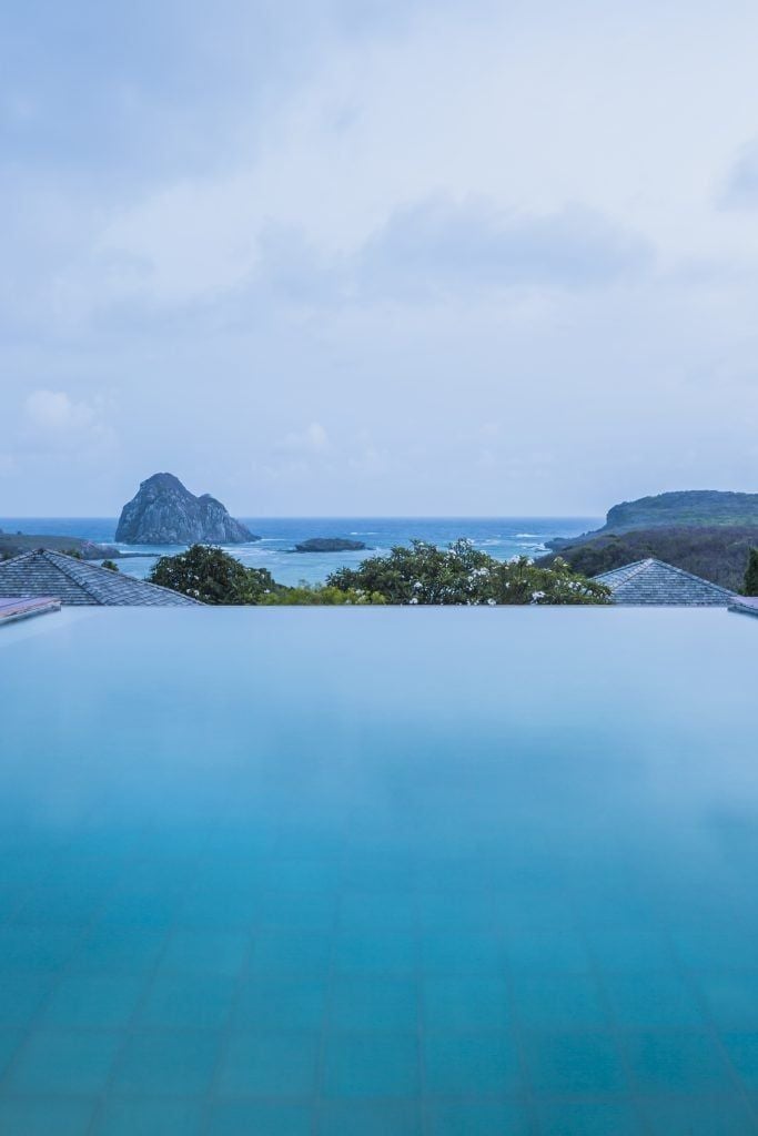 Luxurious Brazilian coastal hotel with panoramic ocean view, featuring modern architecture, infinity pool, and lush tropical landscape at sunset