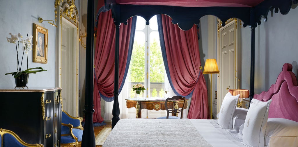 Opulent Imperial Suite with crystal chandelier, ornate gold-framed mirrors, antique furnishings, and plush red velvet seating in Villa Cora