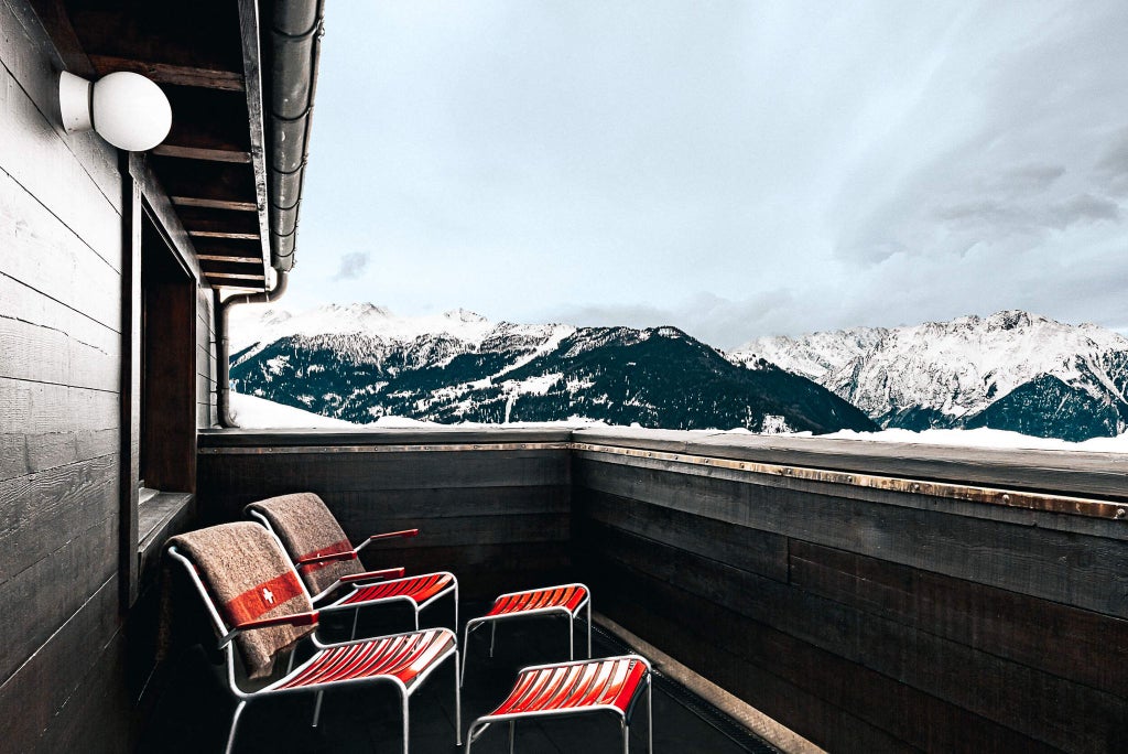 Modern Swiss alpine chalet suite with panoramic mountain views, minimalist wooden furnishings, floor-to-ceiling windows, and elegant contemporary design aesthetic