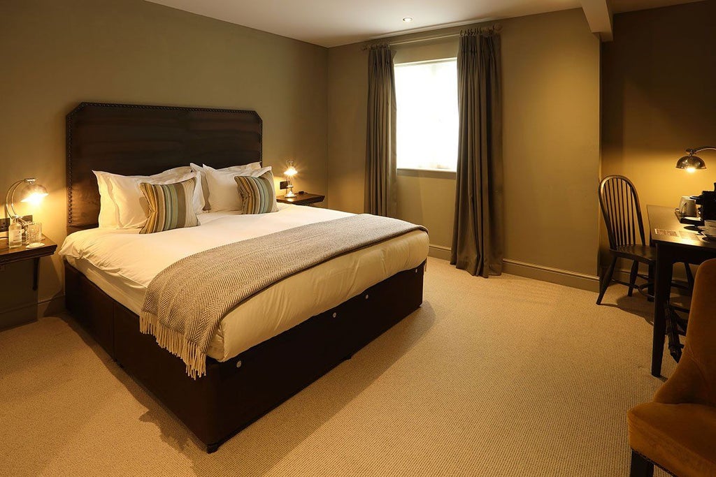 Classic double room with elegant wooden furnishings, crisp white linens, large window, and warm neutral color palette at historic Kings Head Hotel, United Kingdom