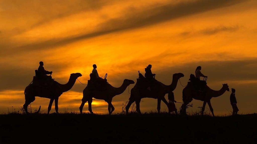 Luxurious safari tents overlooking dramatic Kenyan landscape with sprawling savanna, acacia trees, and distant mountain ranges at scenic wilderness retreat