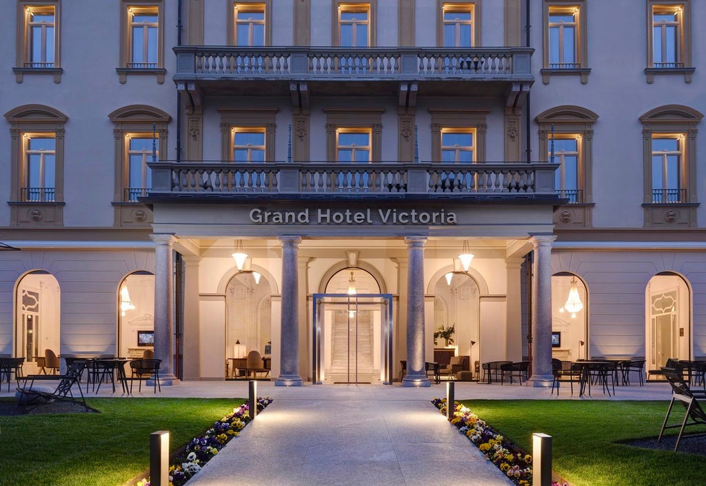 Elegant lakeside Grand Hotel Victoria with ornate Belle Époque architecture, palm trees, and manicured gardens reflecting in Lake Como