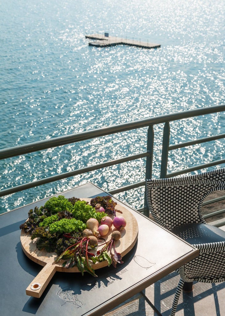 Elegant coastal hotel with blue-teal facade, nestled on rocky cliffs overlooking azure waters of Brittany, showcasing luxurious maritime architectural charm