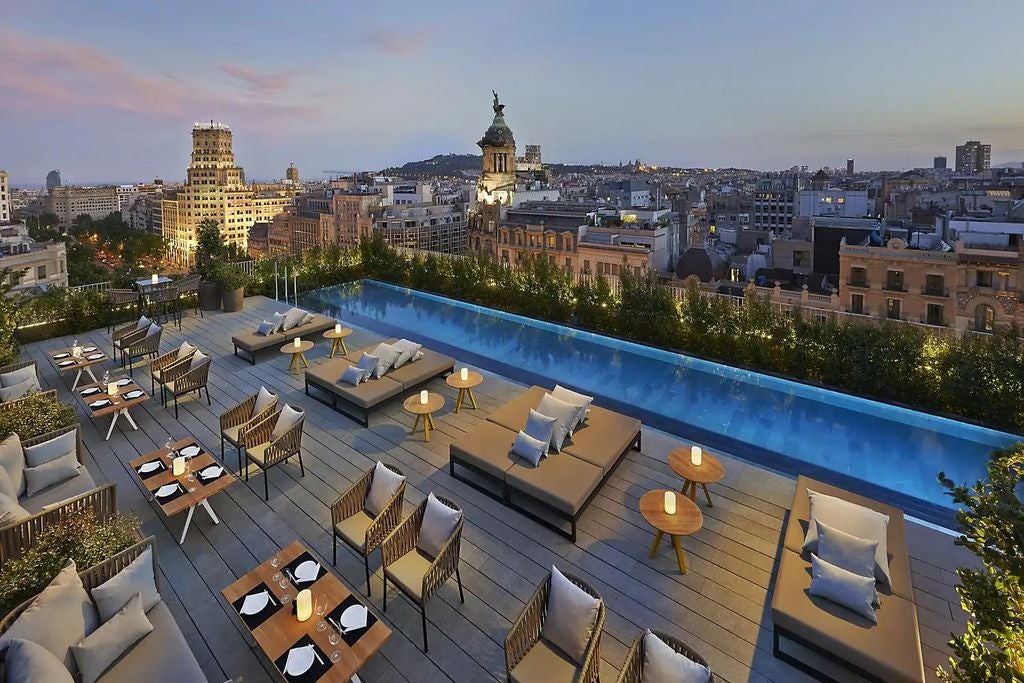 Elegant five-star hotel facade with modern glass windows, ornate stone columns, and luxurious entrance along Barcelona's Passeig de Gracia