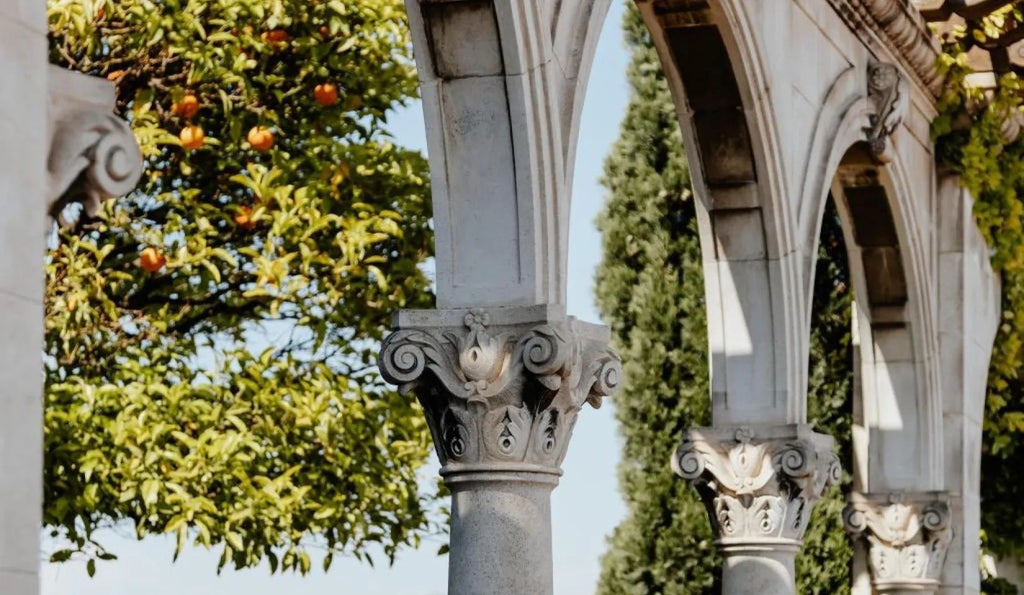 Elegant Spanish luxury hotel with grand facade, ornate balconies, and warm limestone exterior in central urban location at golden hour