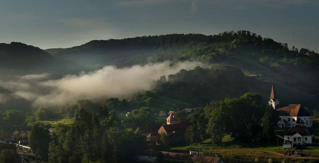 Luxurious restored Saxon manor house nestled in rolling hills of Transylvania, featuring stone walls, wooden details, and pristine countryside landscape