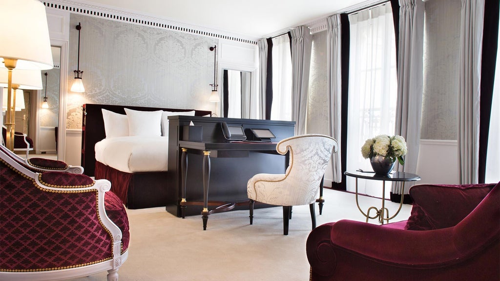 Elegant Parisian hotel suite with plush cream and beige furnishings, ornate chandelier, and floor-to-ceiling windows overlooking city's refined architectural landscape