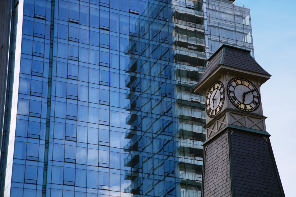 Modern glass skyscraper of Four Seasons Toronto with elegant curved facade, reflecting sunlight, surrounded by upscale Yorkville area