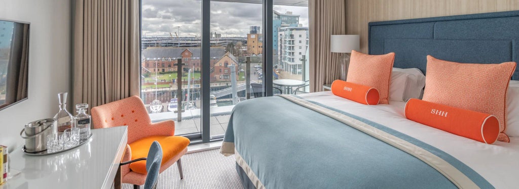 Elegant double room at Harbour Hotel Southampton with soft neutral decor, plush bedding, and inviting Juliet balcony overlooking waterfront scenery