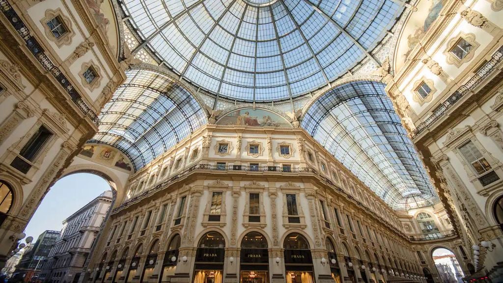 Elegant marble facade of Park Hyatt Milan hotel with ornate architectural details, classic balconies, and lit bronze entrance doors