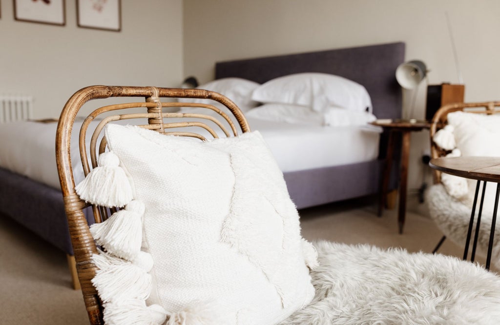 Elegant coastal-inspired hotel bedroom with crisp white linens, plush throw pillows, wooden furniture, and soft natural light in a UK seaside accommodation