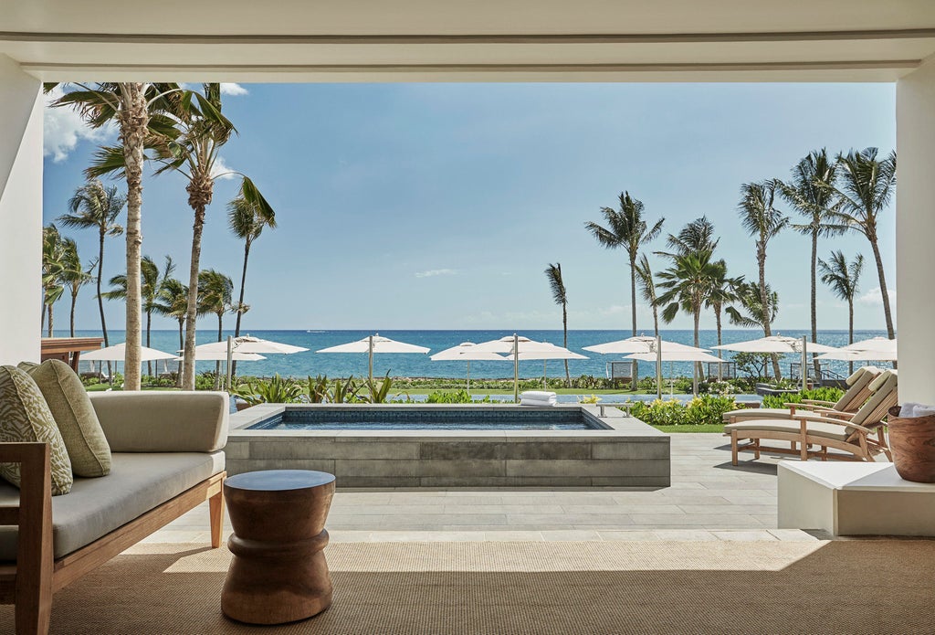 Luxurious beachfront resort with infinity pools cascading toward pristine Ko Olina lagoon, framed by swaying palm trees and ocean view