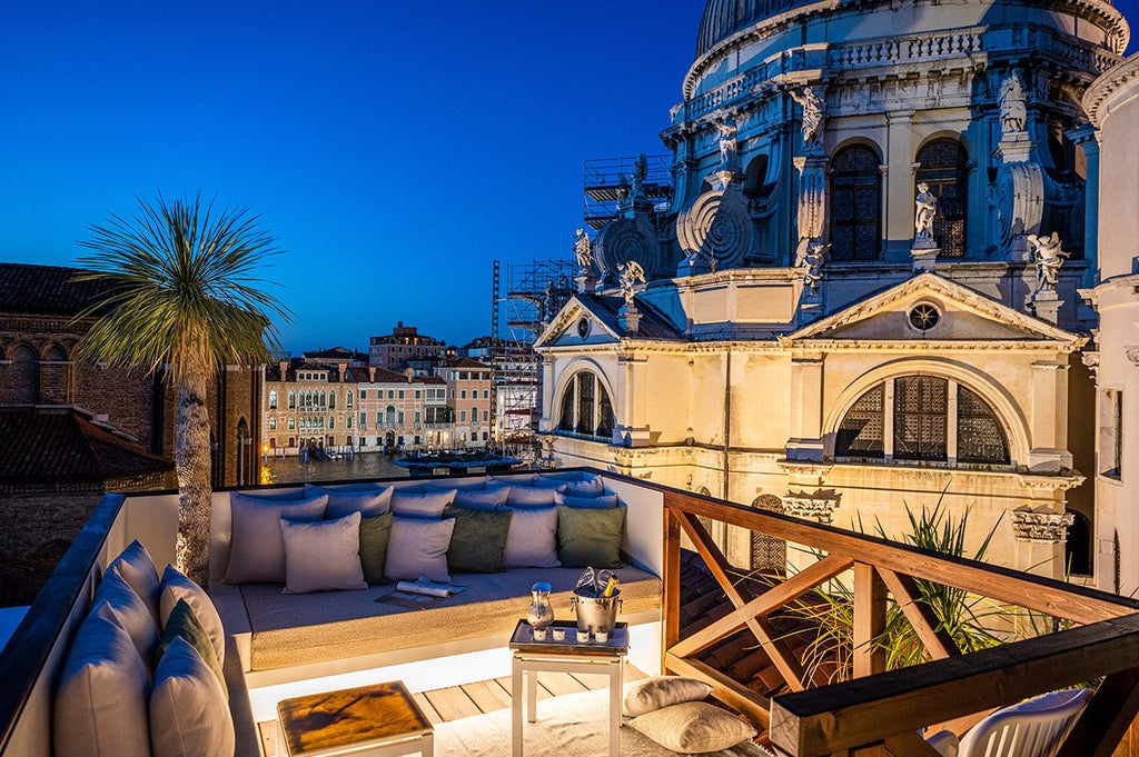 Luxurious Venetian boutique hotel exterior with ornate architecture, adjacent to Basilica Santa Maria della Salute, waterfron