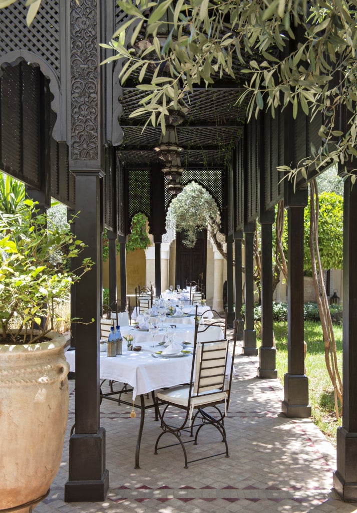 Elegant riad courtyard with traditional Moroccan fountain, orange trees, and arched walkways adorned with intricate tile work and lanterns