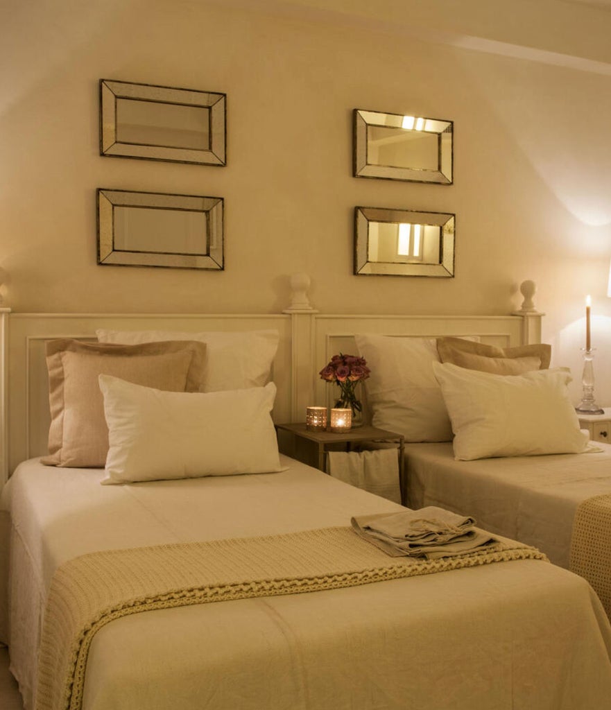 Elegant Italian hotel room with stone walls, vaulted ceilings, rustic chandelier, plush king bed, and traditional wooden furniture