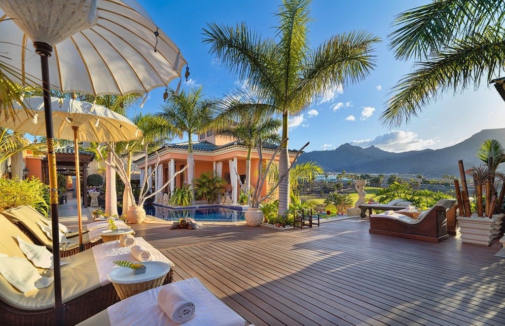 Elegant Mediterranean villa with private infinity pool overlooking lush gardens, white-washed walls and terracotta roof at sunset