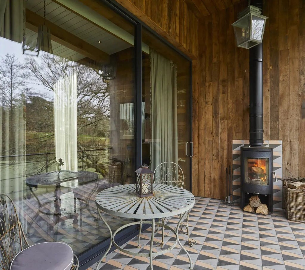 Luxurious forest cabin suite at Lime Wood with rustic wooden walls, plush king bed, and floor-to-ceiling windows overlooking lush greenery in the United Kingdom